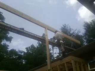 Carpenter setting a ridge beam over a new addition frame — Ice Dam Removal by Roofing Brothers in Tunica