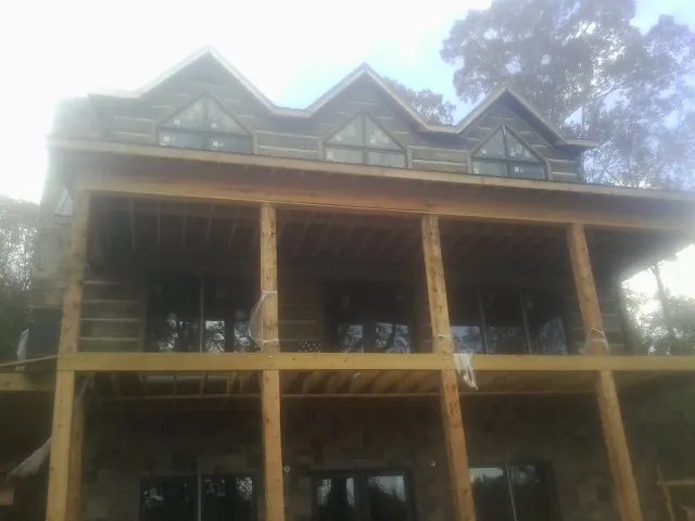 Dormers and porch framing on a large log home under construction — Roof Coating work by our crew in Tunica