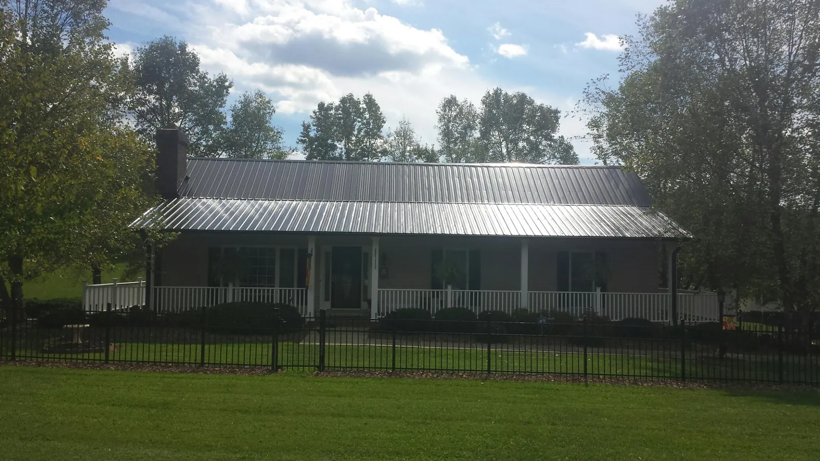 Gray metal roof on a brick ranch with a full width front porch — Gutter Guard Installation work by our crew in Tunica
