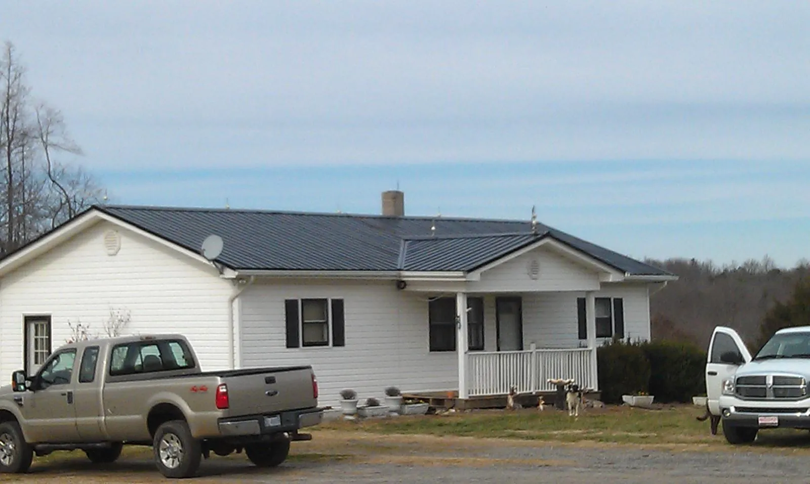 Finished dark metal roof on a white ranch home with work trucks parked in Tunica