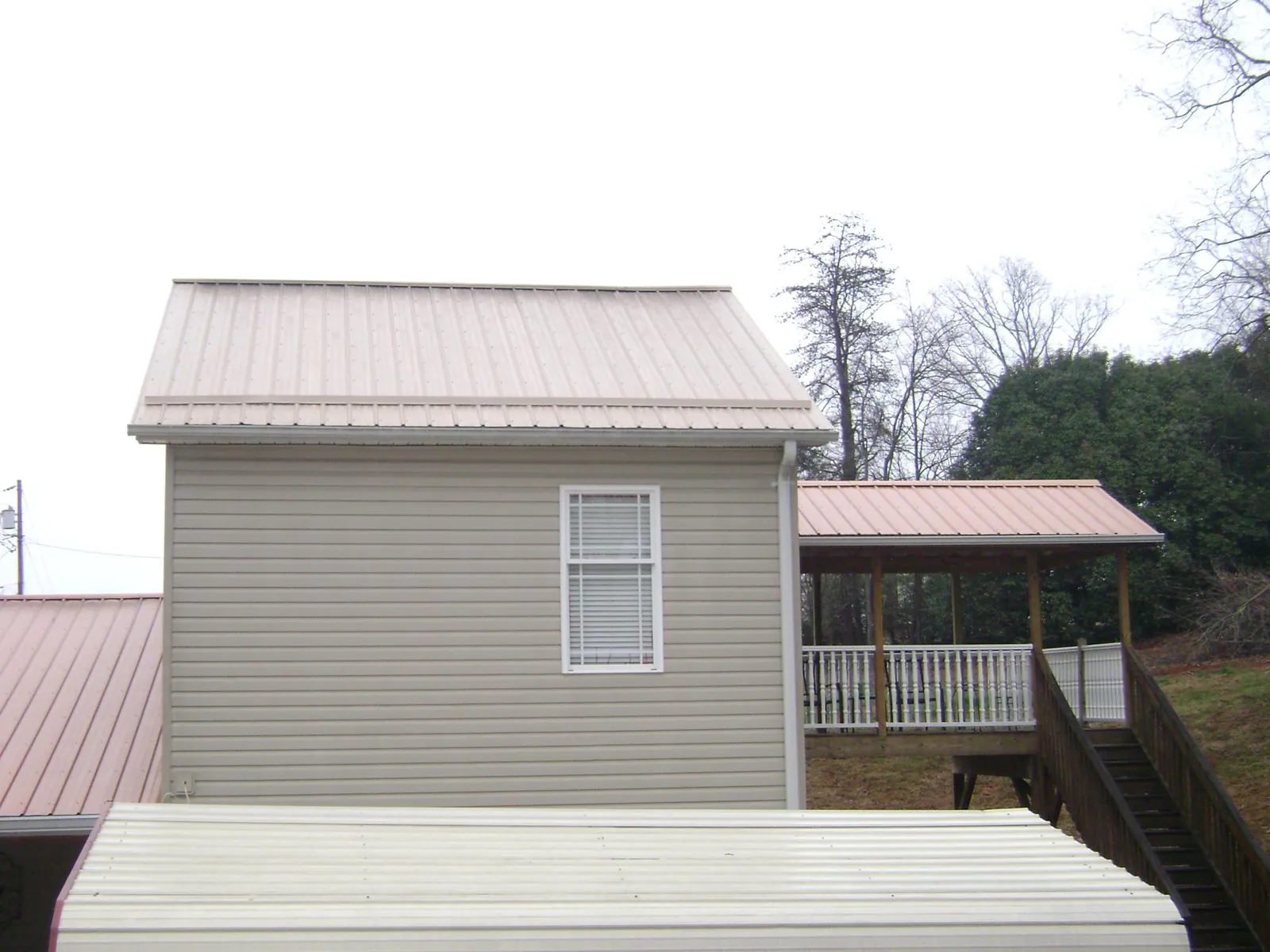 Tan metal roofs on a two story addition and attached porch, from a Roof Replacement job in Tunica