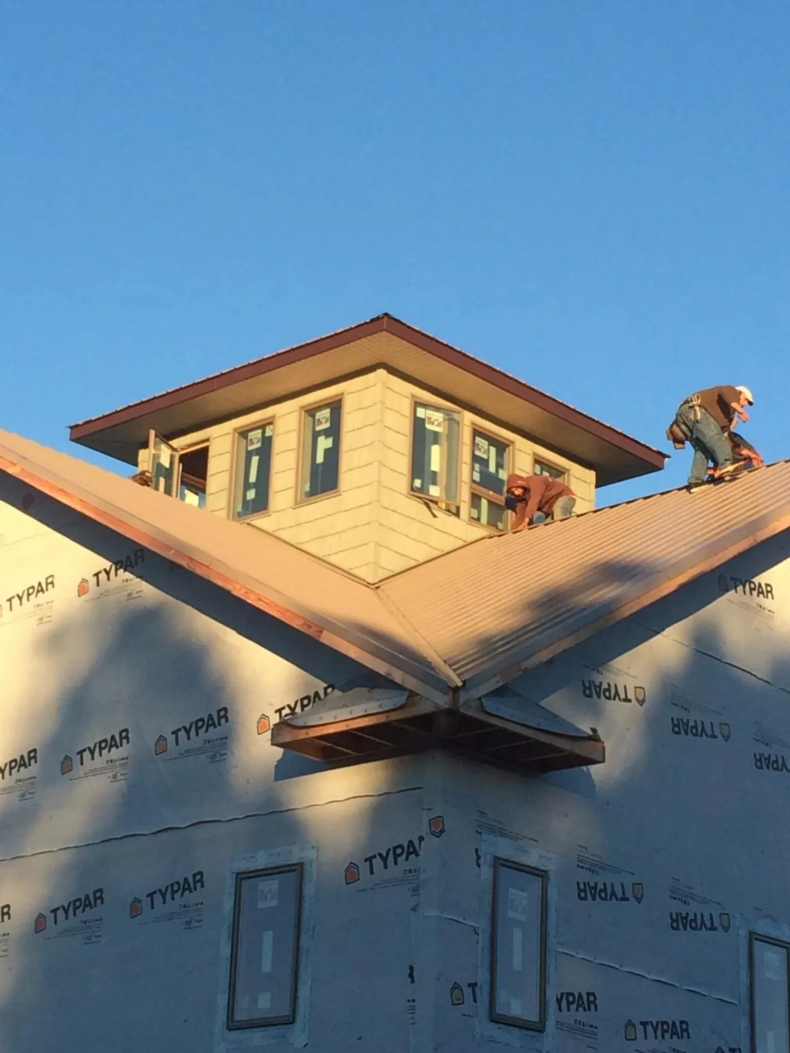 Roofers working around a rooftop cupola on a new metal roof at sunset — Roof Waterproofing in Tunica by Roofing Brothers